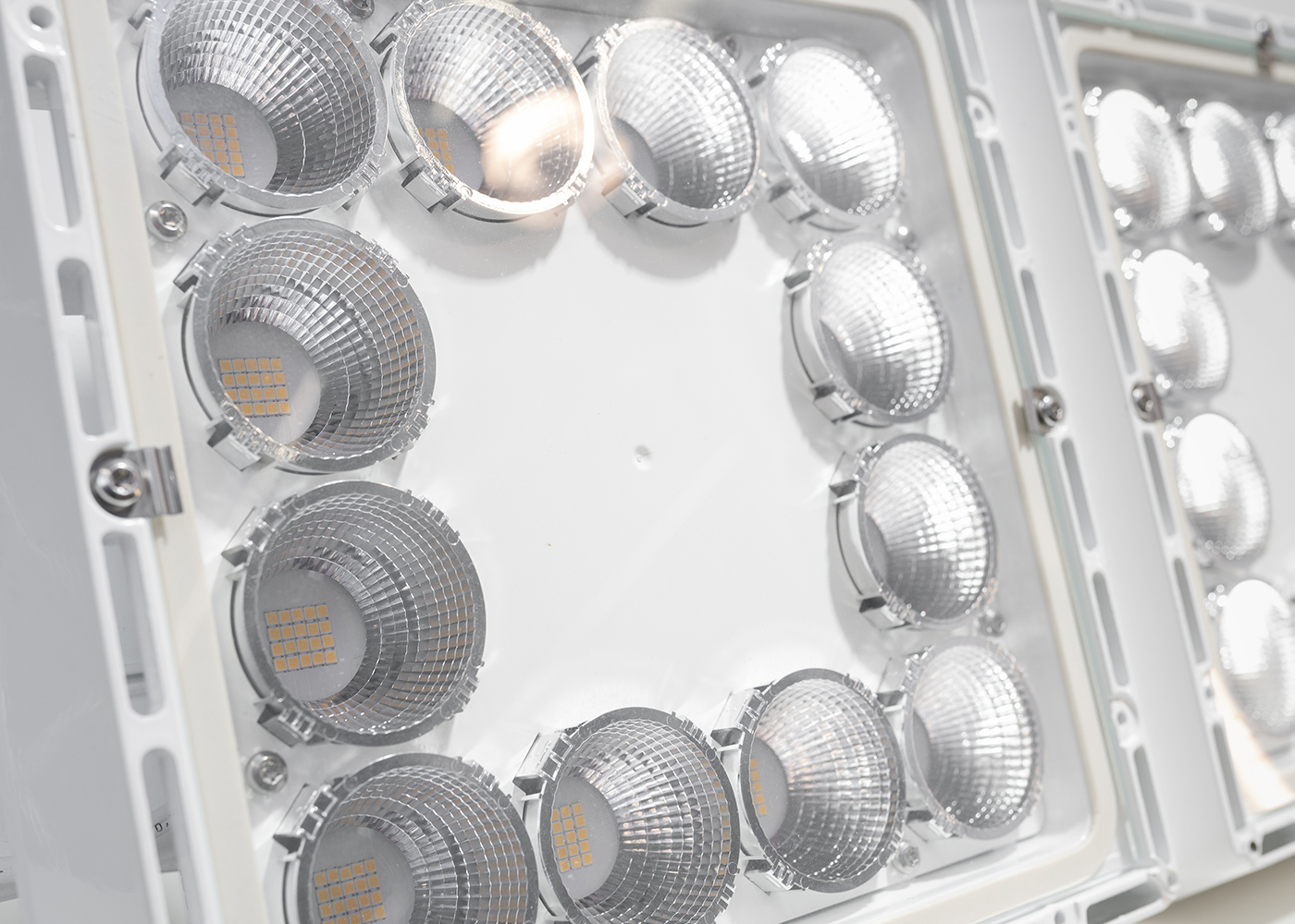 Ausschnitt spiegelnder, aluminiumbeschichteter, runder Reflektoren mit Glasscheibe, im Quadrat angeordnet in der LED Hallenleuchte PRISMPACK™
